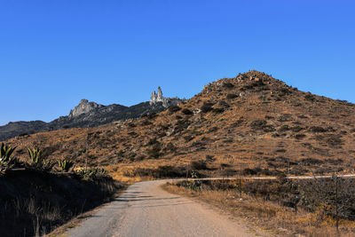 Road by mountain against clear blue sky