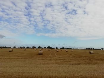 Hay bales on field against sky