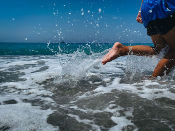 Man splashing water in sea against sky