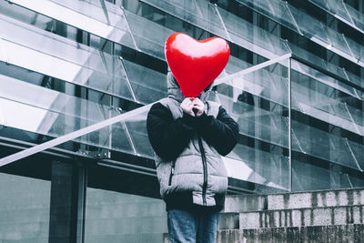 Man holding umbrella with heart shape standing on tiled floor