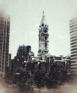 Digital composite image of buildings against cloudy sky