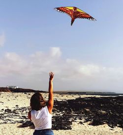 Rear view of person paragliding at beach against sky