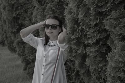 Portrait of smiling young woman standing against tree