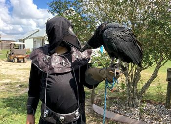 Man standing by pigeons against sky