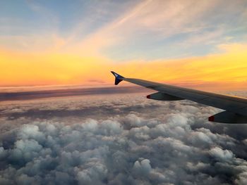 Airplane flying over cloudscape against sky during sunset