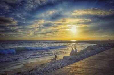 Scenic view of sea against cloudy sky during sunset