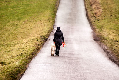 Rear view of woman walking dog