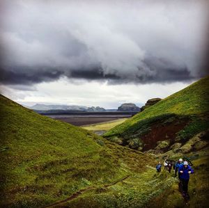 Rear view of people walking on landscape against sky