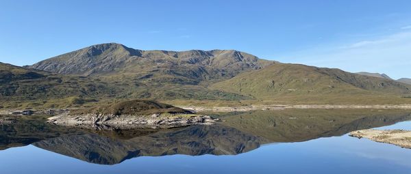 Scenic view of lake and mountains against clear blue sky