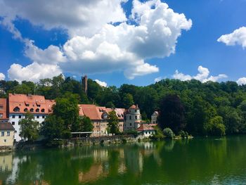 Houses by lake and buildings against sky