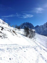 Scenic view of snow covered mountains against blue sky