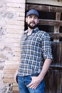 Portrait of man standing against brick wall