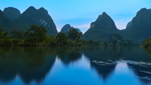 Scenic view of lake and mountains against blue sky