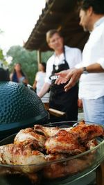 Chicken meat on container with people standing in background