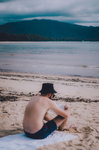 Man sitting on beach against sea