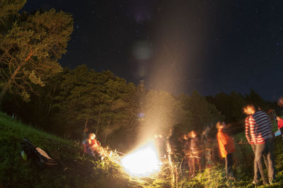 People by illuminated fire at night