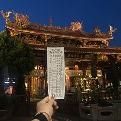 Low angle view of hand on temple against building