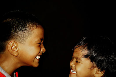Portrait of happy boy against black background