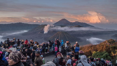 Group of people on mountain against cloudy sky