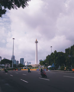 Vehicles on road against cloudy sky