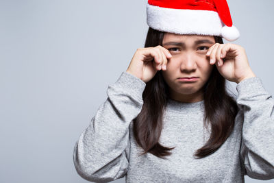 Portrait of sad young woman against gray background