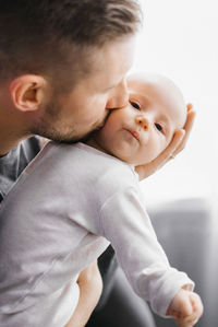 Father holds his newborn baby in his arms and kisses him