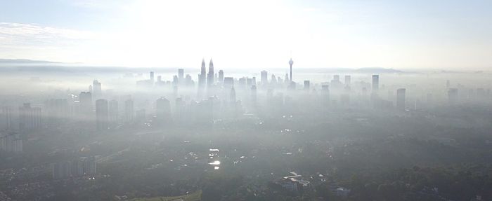 Panoramic view of cityscape against sky during foggy weather