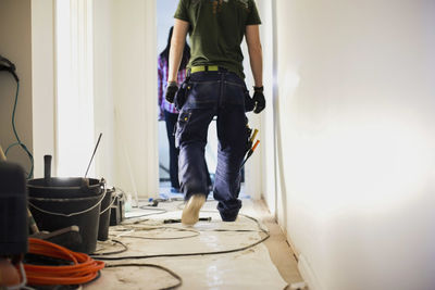 Low section of carpenter walking in corridor at construction site