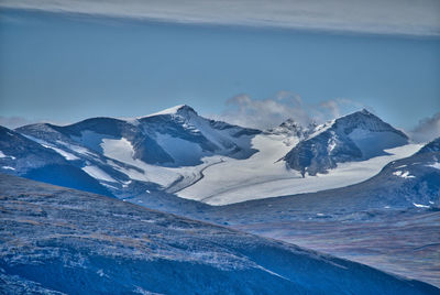 Scenic view of snowcapped mountains against cloudy sky