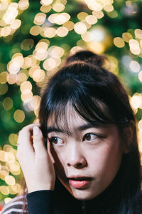 Close-up of young woman looking away against christmas tree