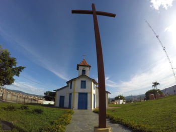 Fish-eye lens view of cross outside church against sky