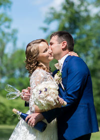 Wedding couple embracing at park on sunny day