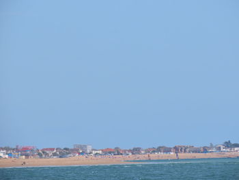 Sea by townscape against clear blue sky