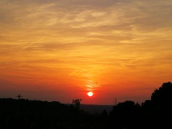 Scenic view of silhouette landscape against orange sky