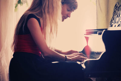 Side view of people sitting on chair by piano