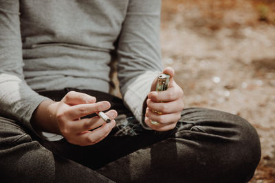 Midsection of person holding cigarette