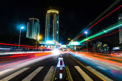 Light trails on road along buildings at night