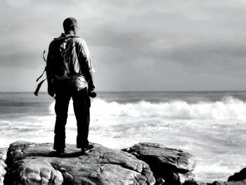 Rear view of man looking at sea against sky