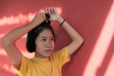 Portrait of woman standing against pink wall