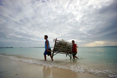 Men standing on beach against sky