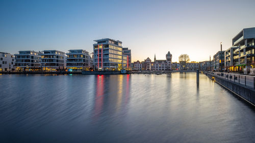 River by buildings against clear sky