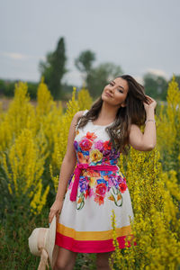 Portrait of beautiful young woman standing on field