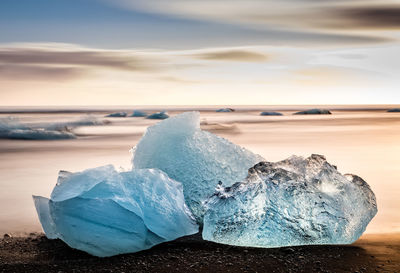 Close-up of ice crystals on sea shore during sunset