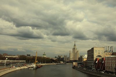 City at waterfront against cloudy sky