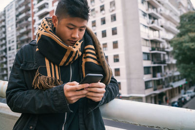 Young man using mobile phone in city