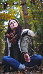 Portrait of smiling young woman sitting in forest