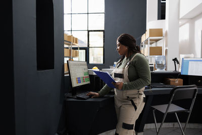 Side view of young woman using laptop while sitting in office