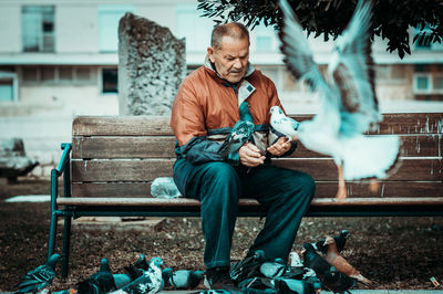 Full length of man sitting on bench in park