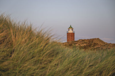 Lighthouse on field against sky