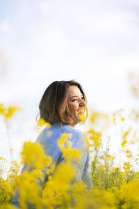 Woman standing by yellow flowers on field